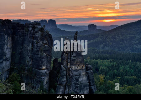 Deutschland, Sachsen, Elbsandsteingebirge, Sandsteinfelsen Brosinnadel mit Falkenstein und Schrammsteine im Hintergrund bei Sonnenuntergang Stockfoto