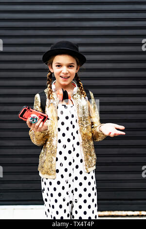 Portrait von lächelnden Mädchen mit Smartphone zu tragen hat, goldene Pailletten Jackett und Polka Dot jumpsuit Stockfoto