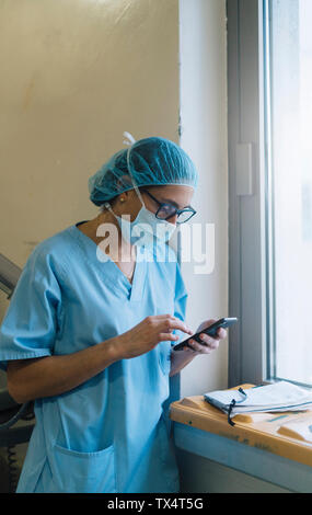 Ärztin mit im Krankenhaus, Smartphone, Vorbereitung für die Chirurgie Stockfoto