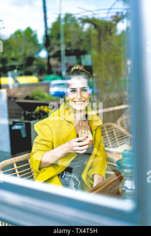 Portrait von lächelnden Frau hinter Fensterglas in einem Cafe Stockfoto