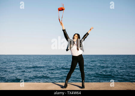 Glückliche Frau spielen mit roten Tasche, das Meer im Hintergrund Stockfoto