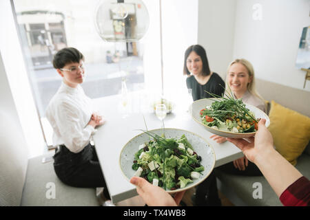 Kellner servieren Salat mit Freunden in einem Restaurant Stockfoto