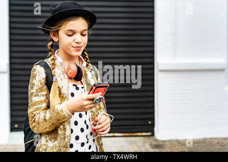 Portrait von Mädchen mit Kopfhörer zu tragen hat und goldenen Pailletten Jacke an Zelle Telefon Stockfoto