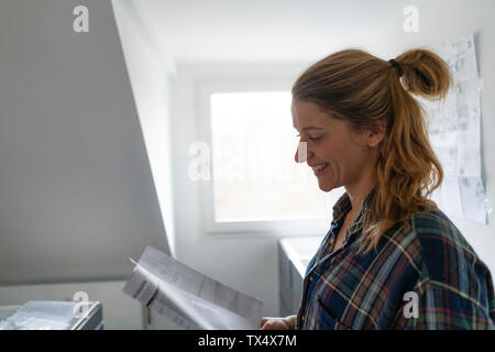 Glückliche junge Frau Studium Einbauanleitung in der Küche Stockfoto