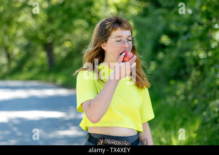 Porträt der jungen Frau mit Brille, mit einem Apfel Stockfoto