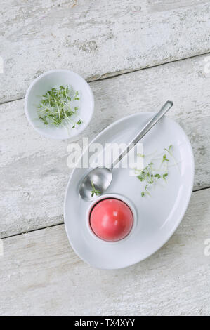 Gefärbte Ostereier in Eierbecher ans Cree in eine Schüssel geben. Stockfoto