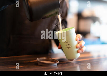 Mann strömenden heißen Milch in Kaution Tasse für Kaffee, close-up Stockfoto