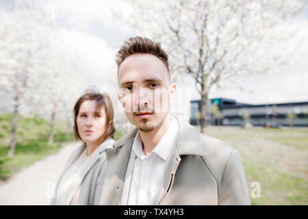 Porträt eines jungen Mannes mit Freundin im Hintergrund, ina Park im Frühling Stockfoto