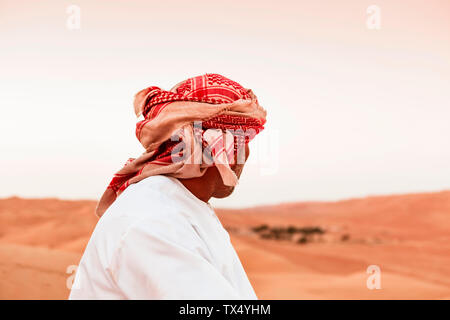 Beduinen in Tracht, die in der Wüste, Rückansicht, Wahiba Sands, Oman Stockfoto