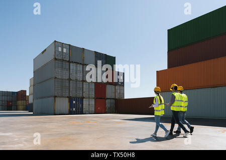 Arbeitnehmer zusammen gehen in der Nähe von Stack von Frachtcontainern auf Industrial Site Stockfoto