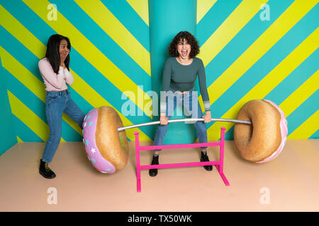 Zwei glückliche junge Frauen an einen Vergnügungspark Spaß mit übergroßen Donuts Stockfoto