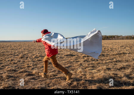 Junge verkleidet als Superheld in Steppen Landschaft läuft Stockfoto