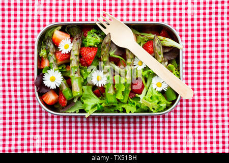 Brotdose mit grünem Salat, grüner Spargel, Erdbeeren und Gänseblümchen Stockfoto