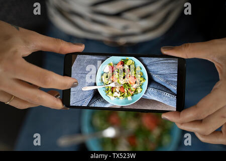 Woman's Hände halten Smartphone, wobei Bild von Salat Stockfoto