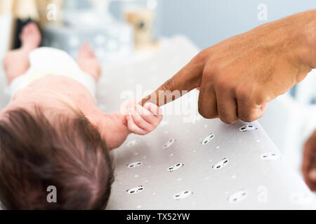 Nahaufnahme des neugeborenen Babys grabbing's Vater Finger auf Wickeltisch Stockfoto