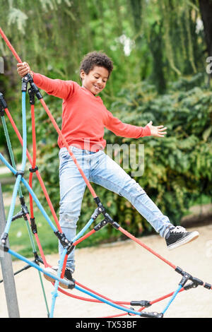 Little Boy spielen auf dem Spielplatz im Park, klettern in einem Jungle Gym Stockfoto