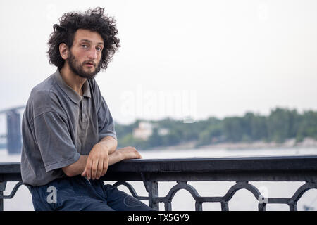 Ukraine, Kiew, 22.06.2019. Porträt einer verträumt und romantisch Obdachloser sitzt auf der Attika an der Küste. Stockfoto