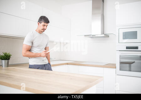 Junge Mann in der Küche zu Hause mit Tablet. Stockfoto