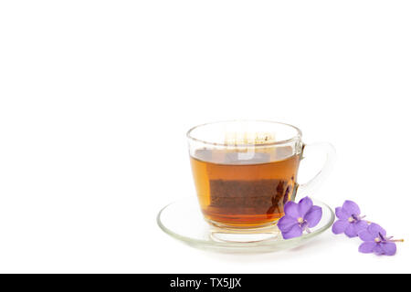 Tee Beutel in einem Glas Schale mit lila Blumen auf weißem Hintergrund. Stockfoto
