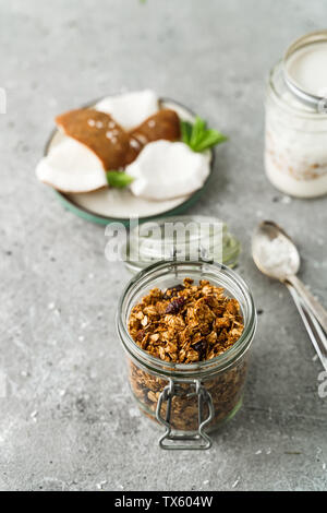 Hausgemachte gebackene Müsli in Glas, coconut Yoghurt auf grauem Hintergrund Stockfoto