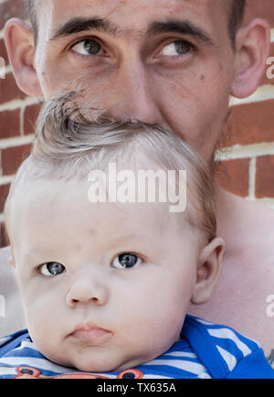Ein Vater mit Tätowierungen hält seinen Sohn in die Arme Stockfoto