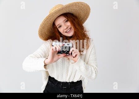 Nahaufnahme, Porträt einer fröhlichen jungen Teenager Mädchen mit Sommer Hut auf weißem Hintergrund, holding Foto Kamera Stockfoto