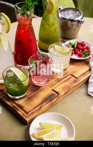 Sommer alkoholfreie Getränke, eine Reihe von limonaden. Limonaden in Krügen auf dem Tisch, die Zutaten, aus dem sie bestehen, sind um angeordnet. Stockfoto