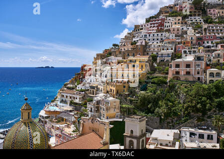 Schönen sonnigen Stadtbild von Positano Hill - Stadt an der Amalfiküste in Italien. Es gibt viele bunte Häuser mit Kirche Santa Maria Assunta auf dem blauen se Stockfoto