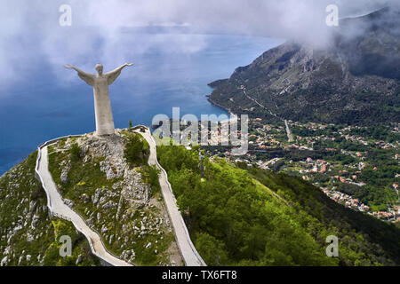 Große Denkmal von Jesus auf der Oberseite des grünen Klippe am Meer Hintergrund in Maratea Hill - Stadt an der Tyrrhenischen Küste in Italien. Antenne horizontal Foto. Stockfoto