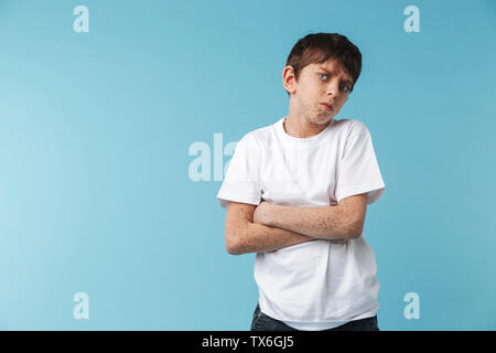 Bild von schweren enttäuscht Boy 10-12 y mit Sommersprossen tragen weiße casual t-shirt an Kamera über blau hintergrund suchen Stockfoto