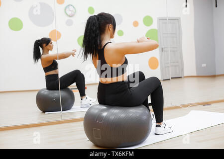 Fitness Frau. Junge attraktive Frau, Push-ups mit Kugel Stockfoto