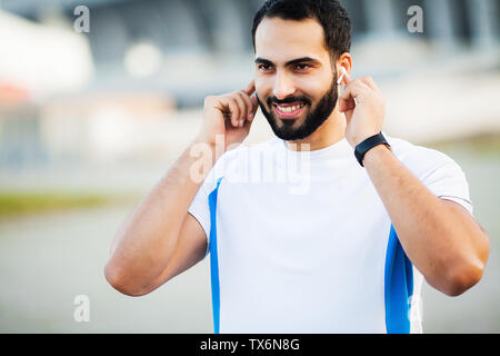 Sport Mann über Kopfhörer zum Hören von Musik auf Morgen laufen im Park Stockfoto