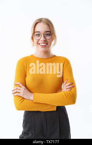 Attraktive junge blonde Frau mit Pullover, die auf weißem Hintergrund Stockfoto