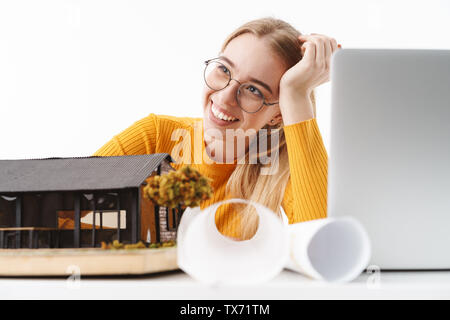 Schöne junge blonde Frau, Architekt, die auf weißem Hintergrund, auf ein neues Projekt an einem Schreibtisch mit Laptop arbeiten Stockfoto