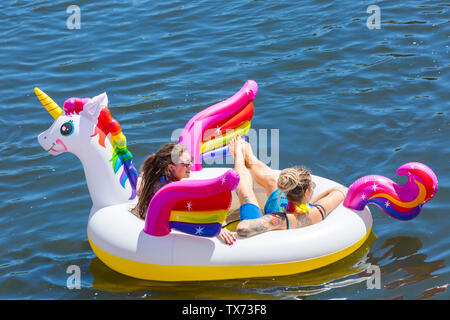 Zwei Frauen Spaß auf aufblasbaren Einhorn aufblasbare auf Dorset Beiboot Tag an Iford entlang des Flusses Stour zu Tuckton, Dorset UK gehen im Juni Stockfoto