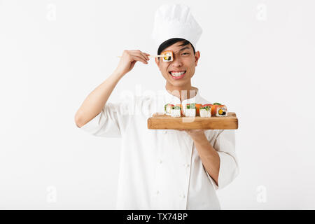 Bild von lächelnden chinesischen chief Mann in Weiß cook einheitliche Halteplatte und Sushi essen mit Stäbchen auf weißem Hintergrund einstellen Stockfoto