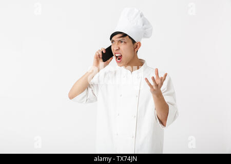 Bild gereizter chinesischen chief Mann in Weiß cook einheitliche und Kochmütze Gespräch am Handy auf weißem Hintergrund Stockfoto