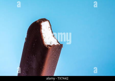 Eis am Stiel in Schokolade Glasur close-up mit Kondensat und Eisbildung Frost im Sommer blauer Himmel gebissen. Eis Textur. Stockfoto