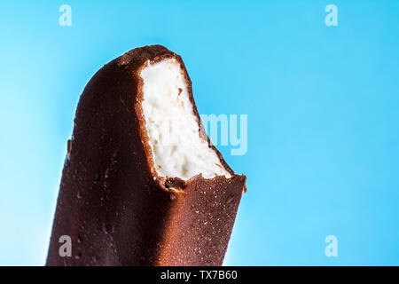 Eis am Stiel in Schokolade Glasur close-up mit Kondensat und Eisbildung Frost im Sommer blauer Himmel gebissen. Eis Textur. Stockfoto