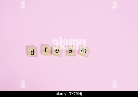 Wort Traum aus kleinen Buchstaben heraus auf einem rosa Hintergrund, Konzept großer Traum, Kopieren, Ansicht von oben Stockfoto