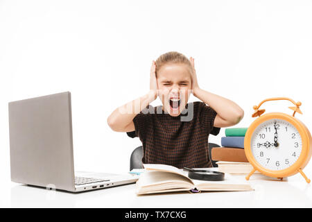 Portrait von unglücklichen Schule Mädchen mit silber Laptop während des Studiums und das Lesen von Büchern in der Klasse auf weißem Hintergrund Stockfoto