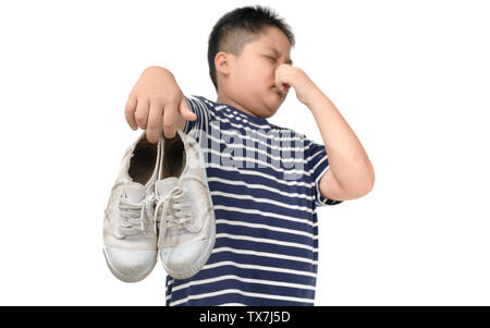 Fat Boy Holding ein Paar muffig und stinkig Schuhe auf weißem Hintergrund angewidert, Stockfoto