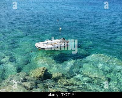 Schlauchboot Motorboot in kristallklarem Wasser in Agia Pelagia, Kreta, Griechenland verankert. Stockfoto