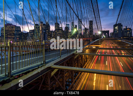 Verkehr die Brooklyn Bridge bei Nacht durch die Skyline von Manhattan, New York, USA Stockfoto