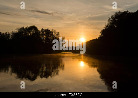 Dämmerung, Sonnenaufgang über Salhouse Broad, den Norfolk Broads, Mai, vom Boot auf Bootsurlaub gesehen, Sonnenaufgang über dem See und Bäume. Stockfoto