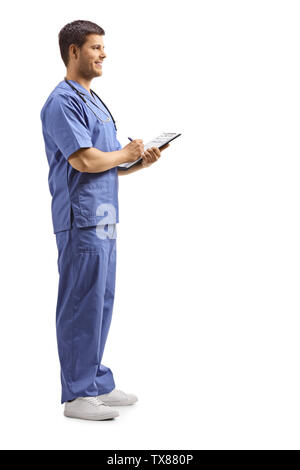 Volle Länge Profil Schoß eines jungen männlichen Gesundheit pratctitioner in einer blauen Uniform schreiben auf einem Klemmbrett auf weißem Hintergrund Stockfoto
