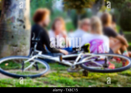 Junge Menschen liegen auf dem Rasen, schickes. Starke Blur, anonyme Menschen auf den Straßen Europas Stockfoto