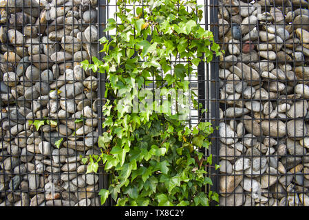 Textur der Steinmauer. Der Zaun aus Stein. Die steinwand ist rund mit schwarzem Stahl gebunden. Design Ideen, Hintergründe, Banner und ar machen Stockfoto