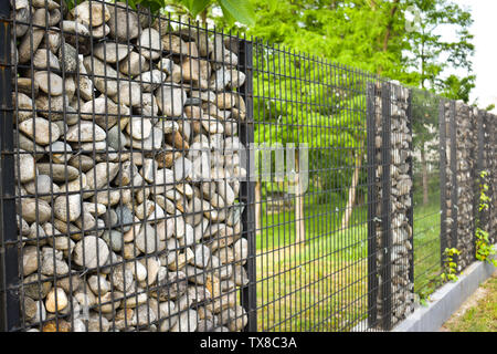Textur der Steinmauer. Der Zaun aus Stein. Die steinwand ist rund mit schwarzem Stahl gebunden. Design Ideen, Hintergründe, Banner und ar machen Stockfoto