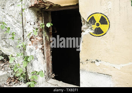 Radioaktive Warnschild auf der Grunge dirty Wall in verlassenen Gebäude aus der Sperrzone. Tschernobyl Pripyat Atmosphäre. Stockfoto